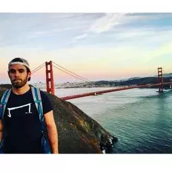 un homme qui porte un M tee shirt noir de la marque Aurelien Magnano devant le pont de San Francisco Californie USA