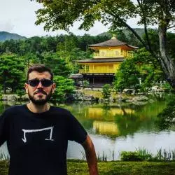 un homme qui porte un M tee shirt noir de la marque Aurelien Magnano devant un lac au japon