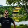 un homme qui porte un M tee shirt noir de la marque Aurelien Magnano devant un lac au japon
