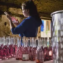 la fabrication du gin rose saint amans-gin-dry-rose-femme-une bouteille dans les mains de dos