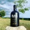 Whisky Notes Fumées-BLACK MOUNTAIN-bouteille posée sur une pierre avec un paysage de campagne à l'arrière